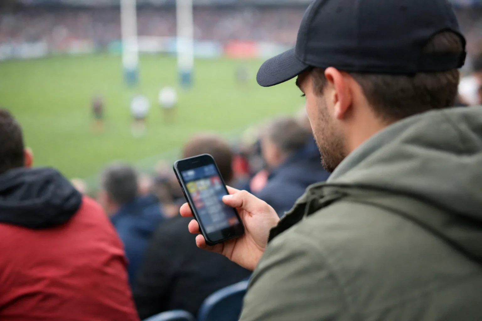 Personne consultant des paris rugby sur son smartphone dans un stade